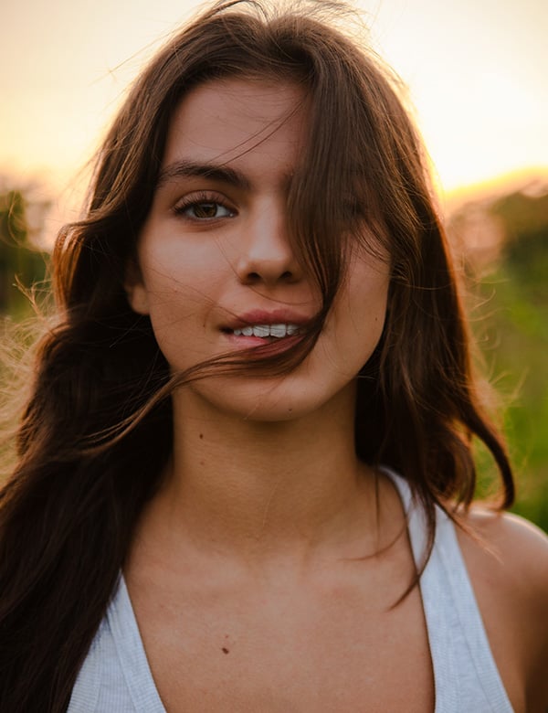 Tienermodel met groene ogen en donkerbruin haar.