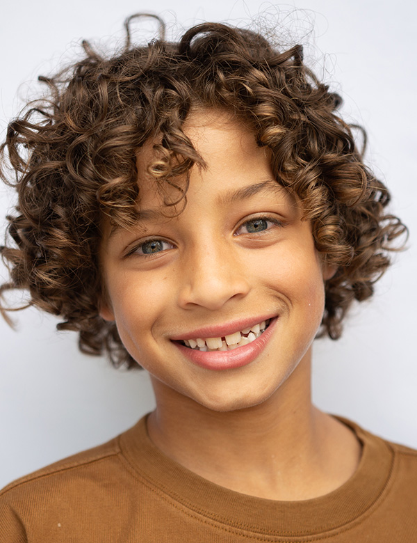 Kindermodel Julian heeft bruin krullend haar en blauwe ogen