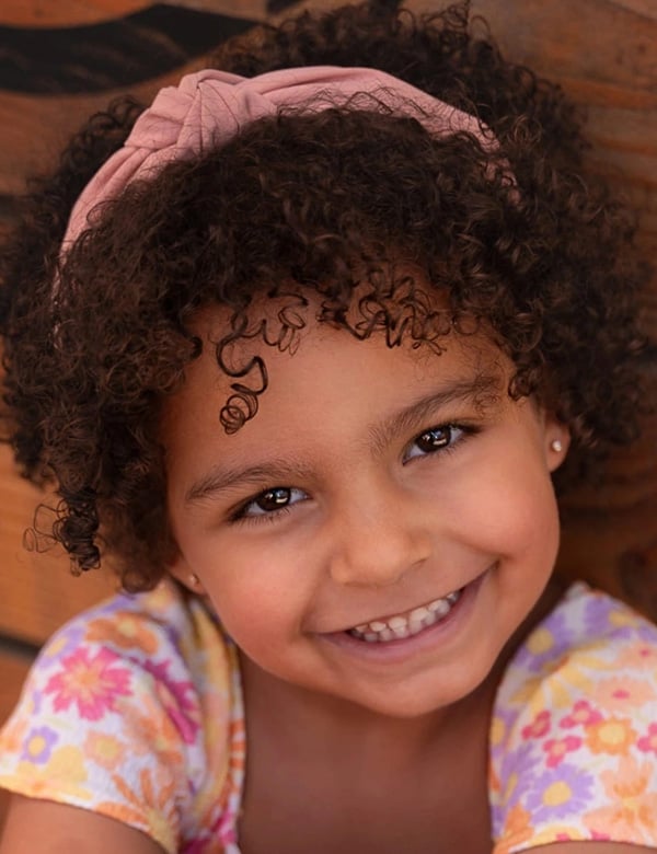 Kinderlijk model met donkerbruin kroes haar en bruine ogen nadine noor.